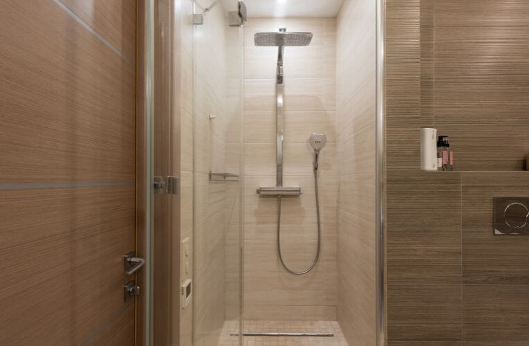 Custom shower renovation in Hornsby by Quality Bathroom Renos with a rainfall shower, handheld spray, and soft beige tiles.